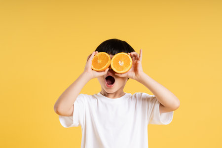 Portrait of adorable asian boy posing on yellow backgroundの写真素材