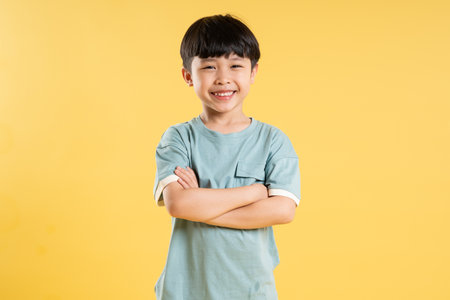 Portrait of adorable asian boy posing on yellow background