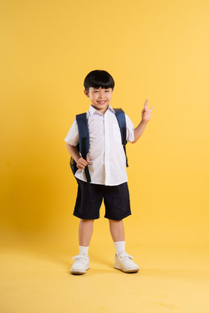 Portrait of adorable asian boy posing on yellow backgroundの写真素材
