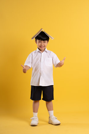 Portrait of adorable asian boy posing on yellow backgroundの写真素材
