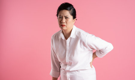 Image of older Asian businesswoman posing on pink backgroundの写真素材