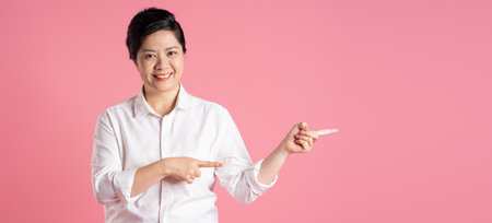 Image of older Asian businesswoman posing on pink backgroundの写真素材