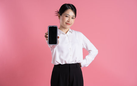 Portrait of beautiful Asian female businessman posing on pink backgroundの写真素材