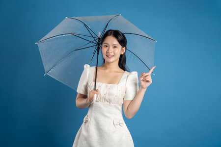 Portrait of beautiful Asian woman posing on blue backgroundの写真素材