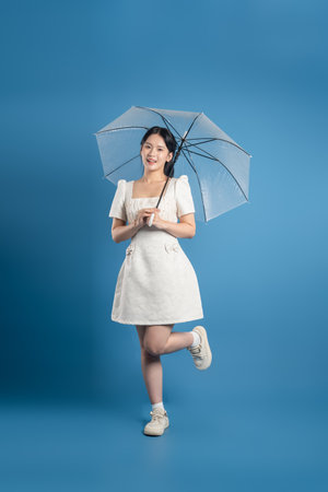 Portrait of beautiful Asian woman posing on blue backgroundの写真素材