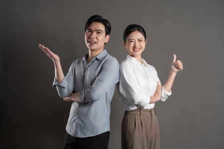 Image of Asian business couple posing on gray background