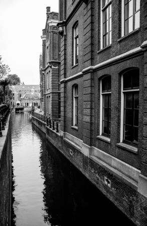 Beautiful narrow water canal reflecting the old building in black and whiteの写真素材