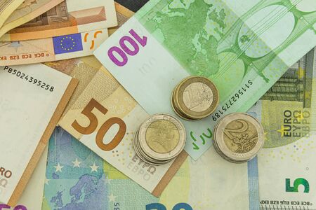 Mix of euro bills and coins stacked onto each otherの写真素材