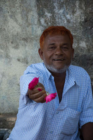 Ahmedabad / India / April 11, 2017: joyful man offering a pink colored flowerのeditorial素材
