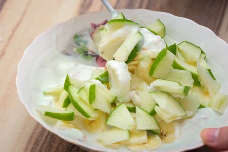 Fresh apple salad of green apple with natural yogurt mixed in a white bowlの写真素材