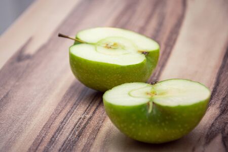 Two half of a green round apple laying on a wooden tableの写真素材