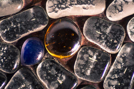 Beautiful light reflection on an orange glass stone and other stonesの写真素材