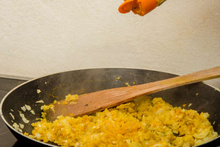 Putting some Indian curry on the mix of onion and other condiments in the hot panの写真素材