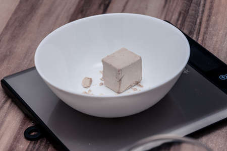 Weigh one cube of yeast on the scales in the kitchenの写真素材