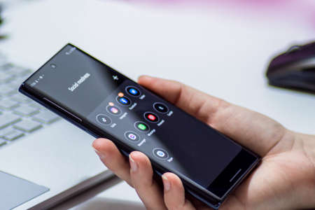 Vienna / Austria / November 14, 2020: Woman's hand holding the black smartphone with social media...