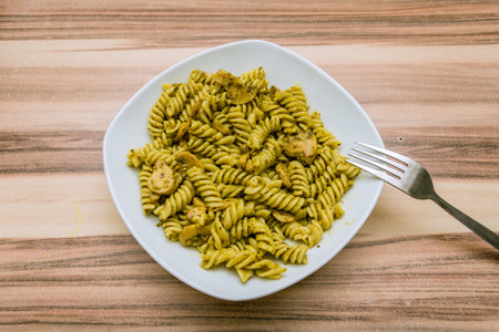 Italian pasta dish with yellow sauce and mushrooms served in white plateの写真素材