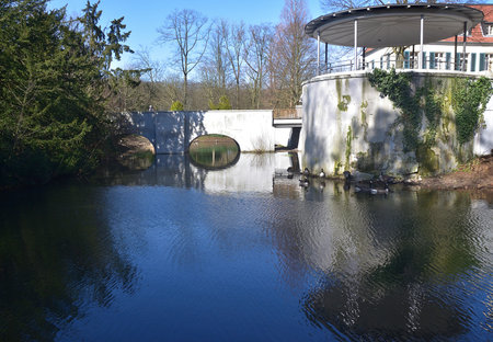 A view of the pond with a bridge in the background and trees in the foreground.の写真素材