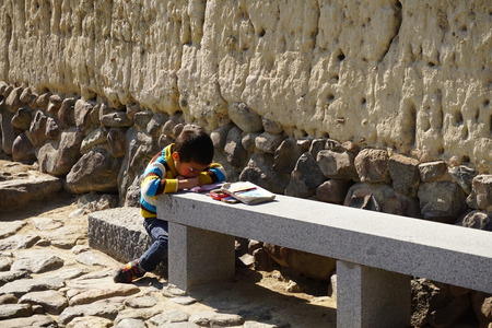 a boy doing homework on the stone benchのeditorial素材