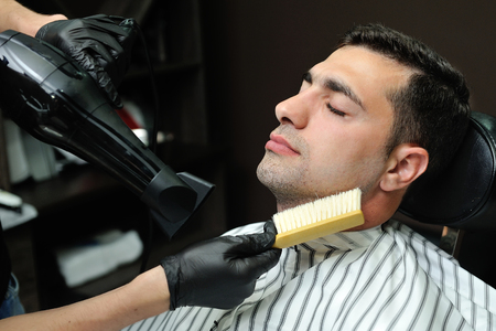 After shaving beard, hairdresser is removed hair from the face with a brush.の写真素材