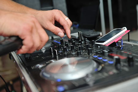 The DJ's hands on the mixing console adjust the parameters.の写真素材