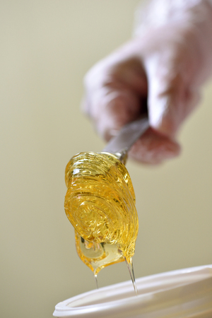 The woman, in the beauty salon, takes out from the jar a pasta for a sugaring, yellow color.の写真素材