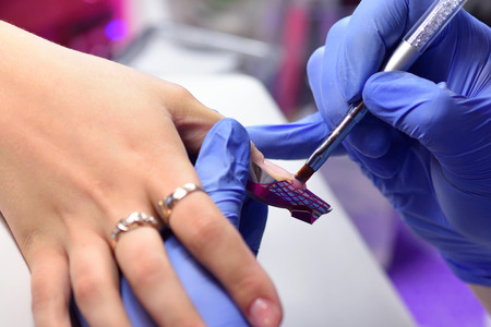 Manicurist with a brush applied to the nails a special gel.の写真素材