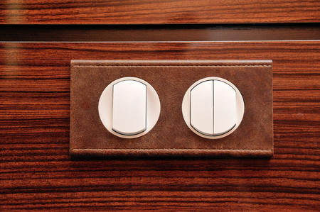 Luxury light switch, leather trimmed and mounted on a wooden polished wall.の写真素材