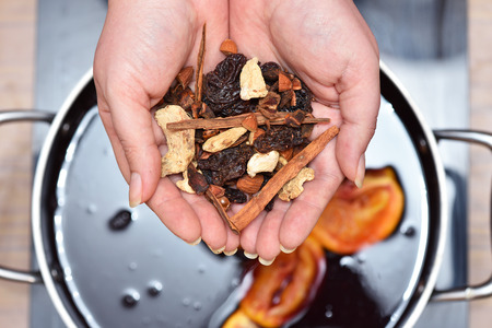 Seasoning for mulled wine in hand over a saucepan of wine.の写真素材