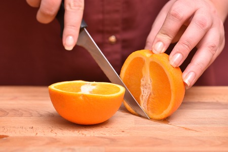 Female hands cut knife orange, juicy and ripe.の写真素材