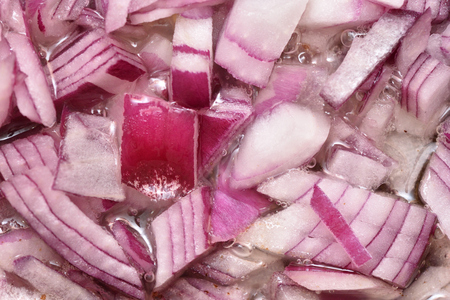 Chopped fresh onion is fried in a frying pan with oil. Close-up.の写真素材