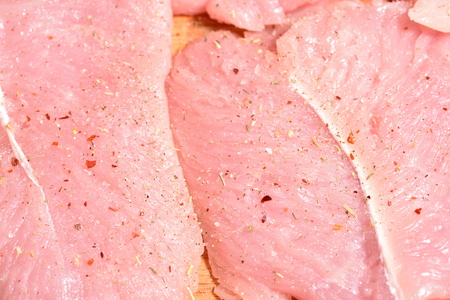 Beautiful and fresh turkey fillet. The fillet of turkey is sprinkled with spices on a cutting board.の写真素材