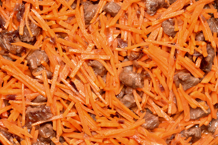 Roasting vegetables and meat in a frying pan with non-stick coating. Onion, carrots and meat. Close-up.の写真素材