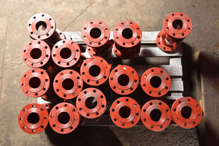 Iron pipes, bases for creating valves, lie on a wooden panel before further processing on a milling...