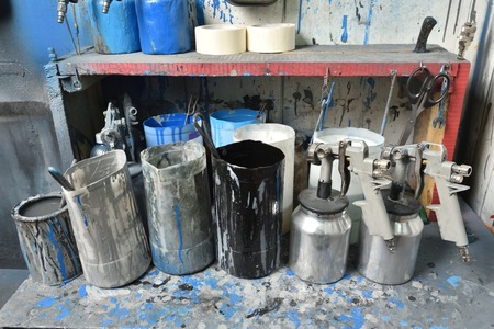 The table in the paint room, everything is stained with paint. On the table are spray guns and...
