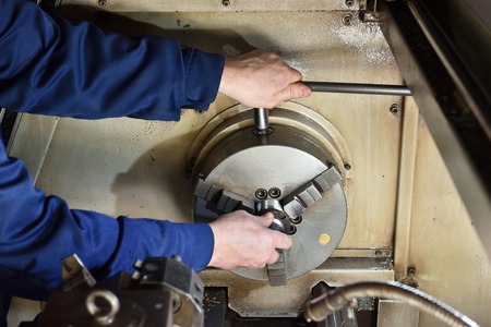 The worker installs a new metal part for processing on the CNC machine. Hands of the worker close...