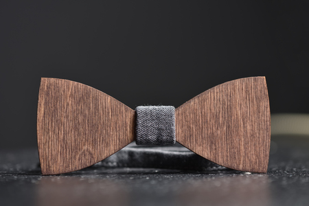 Stylish men's brown wooden bow tie with gray fabric on an iron rough surface. Accessory for brutal men, close upの写真素材
