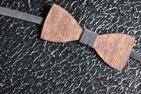 Stylish men's brown wooden bow tie with gray fabric on an iron rough surface. Accessory for brutal...