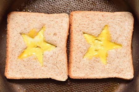 Roasting bread toasts with a star-shaped middle and omelette filled with egg to create a sandwich. Bread is fried for sandwiches in a pan with a non-stick coatingの写真素材