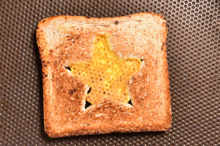 Roasting bread toasts with a star-shaped middle and omelette filled with egg to create a sandwich. Bread is fried for sandwiches in a pan with a non-stick coatingの写真素材