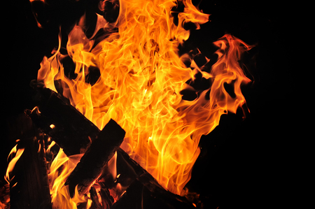 A beautiful flame of a burning fire with wood on a black background.