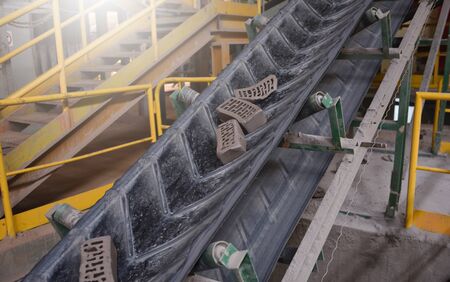 Defective bricks ride on a conveyor belt in a factoryの写真素材
