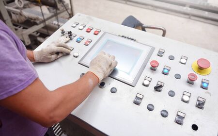 Hands of a worker on a control panel of a brick conveyor.の写真素材