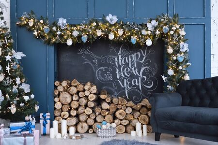 Beautiful decor of the holiday happy new year with prepared wood for the fireplace and the inscription of a happy new year, written in chalk.の写真素材