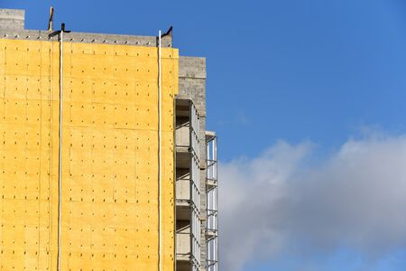 Construction of a residential building and insulation of its external wall with special heat-insulating material. Wall with thermal insulation against the blue skyの写真素材