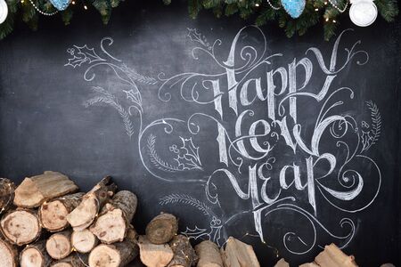 Beautiful inscription on a chalkboard, happy new year, decor and firewood for a fireplace.