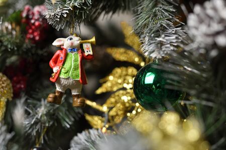A decoration in the form of a bunny with a musical trumpet hanging on a Christmas tree