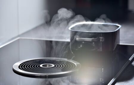 Electric induction cooker with built-in ventilation and extractor hood which draws steam from boiling water in a panの写真素材