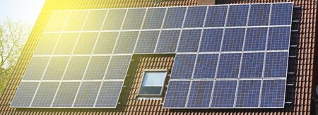 Solar panels installed on the roof of a house with tiles in Europe against the background of a blue...