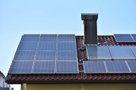 Solar panels installed on the roof of a house with tiles in Europe against the background of a blue...