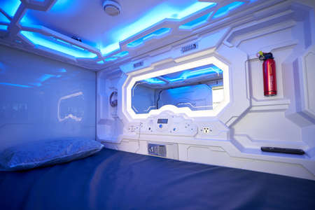 The interior of the capsule hotel with a mirror and a fire extinguisher. Airport capsule hotel for touristsのeditorial素材